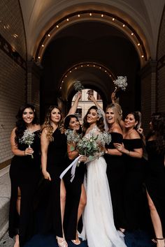 a group of women standing next to each other in front of a building holding bouquets