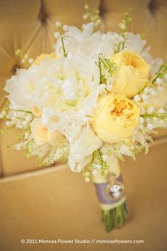 a bridal bouquet with yellow roses and white orchids on a couch in the living room