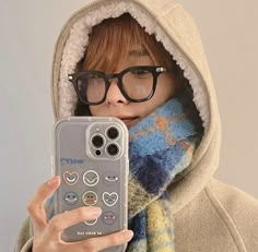 a woman wearing glasses holding up a cell phone