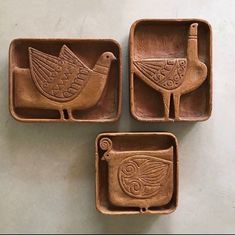 three brown trays with birds on them sitting on a white counter top next to each other