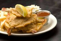 a white plate topped with fried food next to french fries and dipping sauce on top of it