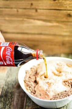 a person pouring coke into a bowl of ice cream