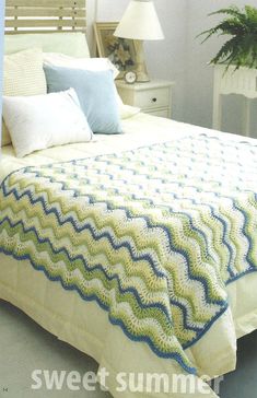 a white bed with blue and green crocheted bedspread