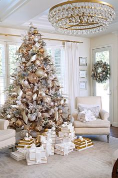 a decorated christmas tree in a living room with gold and silver ornaments on the top