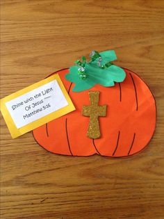 an orange paper pumpkin with a cross on it and a note attached to the front