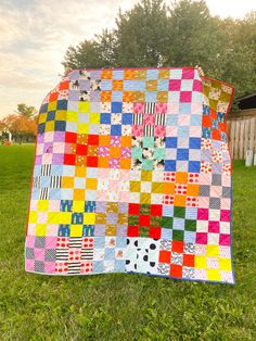 a multicolored patchwork quilt on the grass