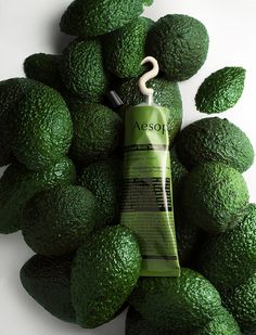 an avocado is surrounded by green leaves and a tube of sunscreen on top