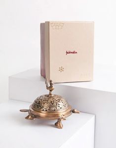 a golden bell sitting on top of a white counter next to a book and box