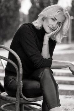 a black and white photo of a woman sitting on a chair with her hand under her chin