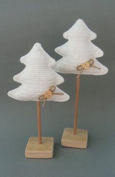 two white crocheted christmas trees on wooden bases with scissors in the middle one has a bow