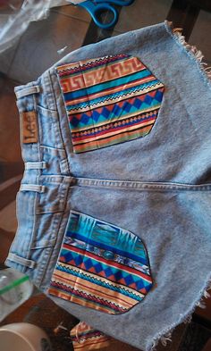 a pair of jean shorts with colorful designs on them