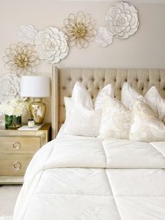 a white bed topped with lots of pillows next to a night stand and nightstands