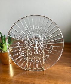 a glass plate sitting on top of a wooden table next to a potted plant