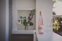 a bottle of wine sitting on top of a white counter next to two empty glasses