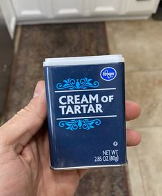 a hand is holding a cream of tartar in front of a white refrigerator door