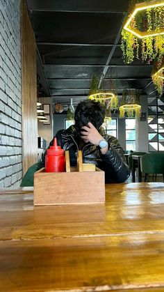 a person sitting at a wooden table in front of a box with ketchup on it