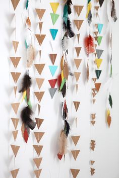 there are many different colored feathers hanging on the wall