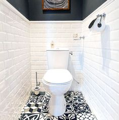 a white toilet sitting in a bathroom next to a black and white tile flooring