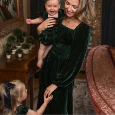 a woman in a green dress holding a baby