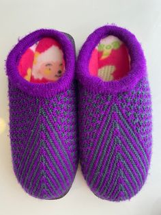 Each hand-made slipper is unique - no two are alike! Foam and soft fleece lining inside keep your feet warm and the treaded bottoms keep them safe inside or out! Made of acrylic yarns and man-made sole Hand Knitted Round Toe Slippers For Winter, Hand-knitted Round Toe Winter Slippers, Hand Knitted Round Toe Winter Slippers, Cozy Knitted Slippers With Round Toe, Cozy Yarn Slippers With Round Toe, Purple Winter Slippers With Round Toe, Purple Round Toe Winter Slippers, Casual Winter Yarn Slippers, Comfortable Purple Round Toe Slippers