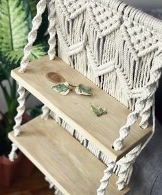 a white macrame chair with some green leaves on it's backrest