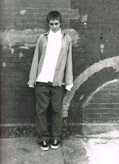 a young man standing in front of a brick wall with his hands on his hips