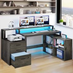 a computer desk with two monitors on top of it next to a book shelf filled with books