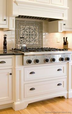 a stove top oven sitting inside of a kitchen next to white cabinets and wooden floors