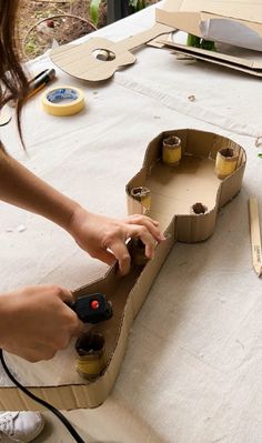 a woman is making a cardboard boat out of empty boxes and glues it on the table