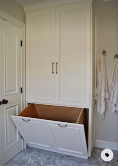 a white cabinet with two open doors and some towels hanging on the wall next to it