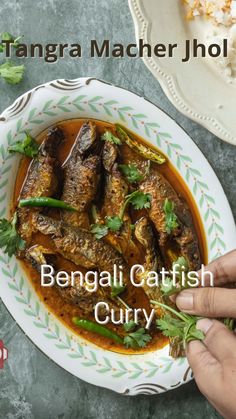 the cover of bengal gattish curry is shown on a plate with a hand reaching for it