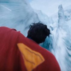 a man in red jacket standing next to an iceberg