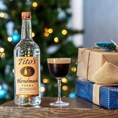 a bottle of liquor next to a glass filled with liquid on a table in front of a christmas tree