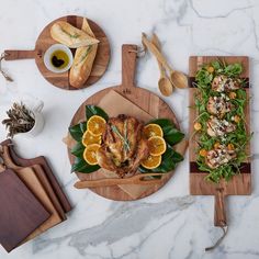 an assortment of food on wooden cutting boards and serving utensils laid out on a marble counter top