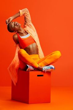 a woman sitting on top of a red box with her arms behind her head and legs crossed