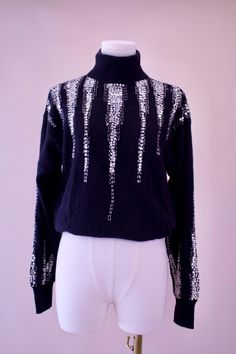 a mannequin wearing a black and white sweater with silver sequins on it