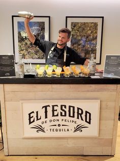 a man standing behind a counter filled with drinks