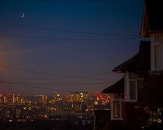 the city skyline is lit up at night, with power lines running across the foreground