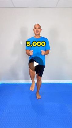 a man standing in front of a blue mat with the number 5, 000 on it