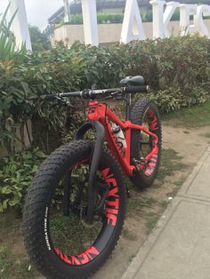 a red and black bike parked next to some bushes