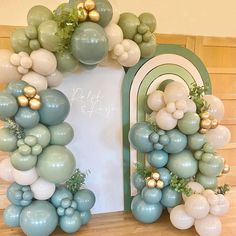 an arch made out of balloons and greenery is displayed in front of a mirror