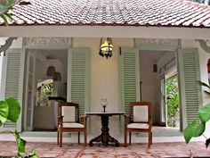 two chairs and a table in front of green shuttered windows