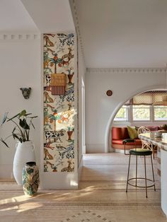 a living room filled with furniture next to a tall white vase on top of a hard wood floor