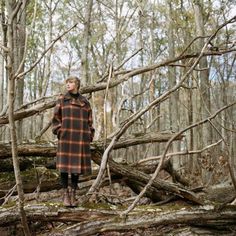 a woman standing on top of a fallen tree in the woods