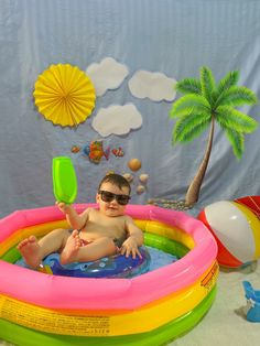 a little boy sitting in an inflatable pool with a frisbee and sunglasses on