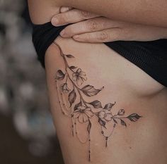 a close up of a woman's stomach with flowers and leaves tattooed on it