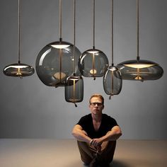 a man sitting on the floor in front of some lights hanging from it's ceiling