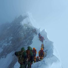 a group of climbers climbing up the side of a snow covered mountain in cold weather