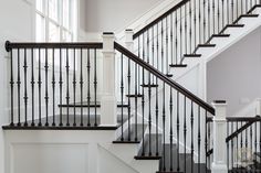 a white staircase with black railing and handrails