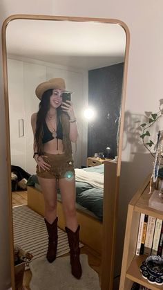 a woman taking a selfie in front of a mirror with her cowboy hat on